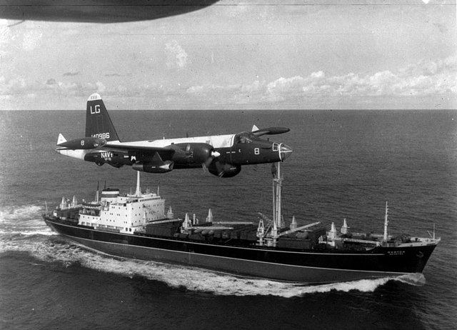 Old photo of a plane flying over a ship